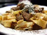 Pappardelle al cinghiale fumanti, con pezzi di carne succulenta e una spolverata di parmigiano.