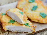Deliziose cotolette di pollo dorate, tagliate a metà per mostrare la succosa carne bianca, guarnite con prezzemolo fresco.
