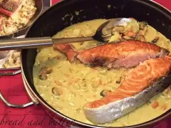 Delizioso trancio di salmone in padella con una cremosa salsa gialla e cozze.