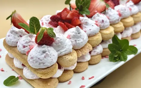 Delizioso tiramisù alle fragole, un dolce a strati con savoiardi, crema rosa e fragole fresche, guarnito con menta.