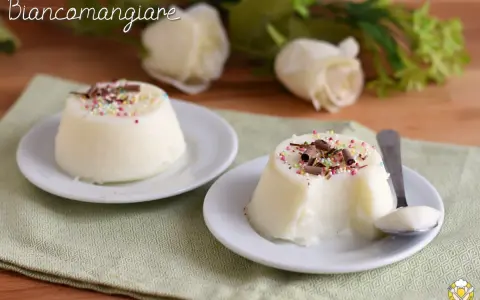 Biancomangiare ricetta originale siciliana: due dolci al cucchiaio bianchi, guarniti con codette colorate e scaglie di cioccolato, su piattini bianchi.