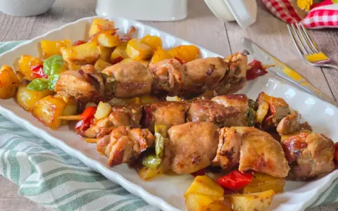 Spiedini di carne succulenti con patate arrosto e peperoni colorati, un piatto invitante e saporito.