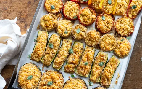 Verdure gratinate al forno: zucchine, melanzane, pomodori e peperoni ripieni di pangrattato e erbe aromatiche, cotti su una teglia.
