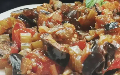 Un piatto invitante di caponata di verdure, con melanzane, pomodori e sedano cotti a puntino.