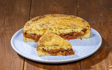 Pitta di patate ripiena di sugo, olive e cipolle, con una crosta dorata di pangrattato.