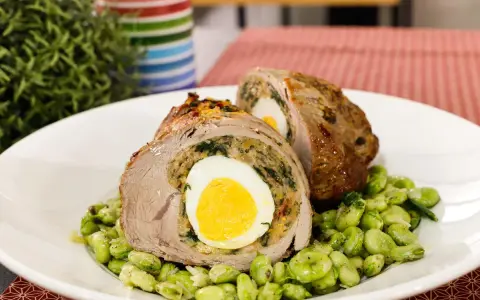 Fettina di carne ripiena con uovo sodo e spinaci, servita su un letto di fave.