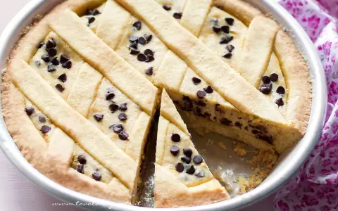 Una deliziosa crostata di ricotta con gocce di cioccolato, con una fetta tagliata per mostrare il ripieno cremoso.