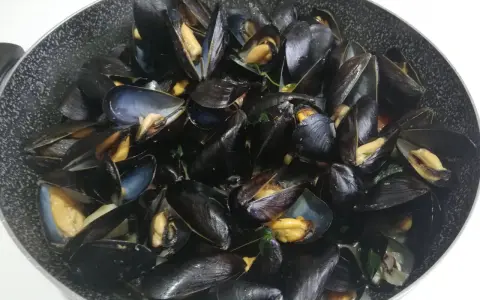 Un saporito sautè di cozze appena cucinato, con gusci aperti che rivelano la polpa succulenta.