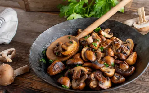 Funghi in padella dorati e saporiti, guarniti con prezzemolo fresco, pronti per essere gustati.