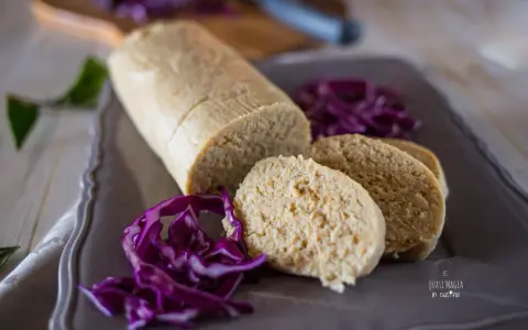 Un gustoso salame di tonno, affettato e servito con cavolo rosso tritato su un piatto grigio.