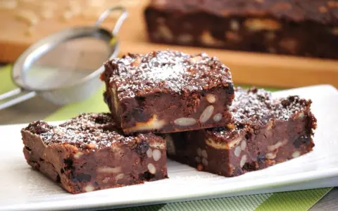 Fette di torta di pane al cioccolato, ricche di frutta secca e noci, spolverate di zucchero a velo.