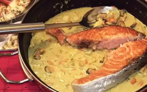 Delizioso trancio di salmone in padella con una cremosa salsa gialla e cozze.
