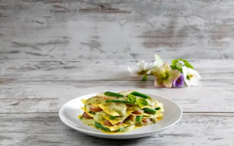 Lasagne al pesto con fagiolini e patate, un piatto colorato e gustoso su un tavolo di legno.