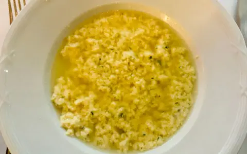 Stracciatella alla romana in una ciotola bianca, un piatto caldo e confortante con uova, parmigiano e prezzemolo.