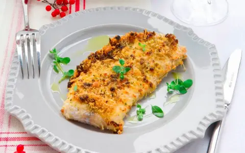 Delizioso merluzzo impanato al forno, dorato e croccante, guarnito con erbe fresche e servito su un piatto grigio.