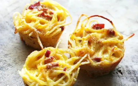 Tre deliziose frittate di pasta, dorate e con pezzetti di pancetta, pronte per essere gustate.