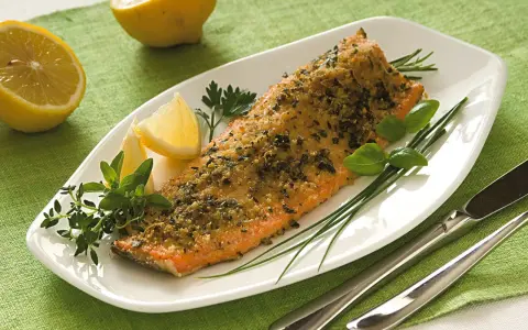 Deliziosa trota salmonata al forno, croccante e profumata, servita con limone fresco e erbe aromatiche.