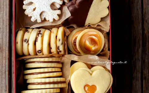Scatola piena di biscotti al burro: a fiocco di neve, al cioccolato, con ripieno di caramello e a forma di cuore.