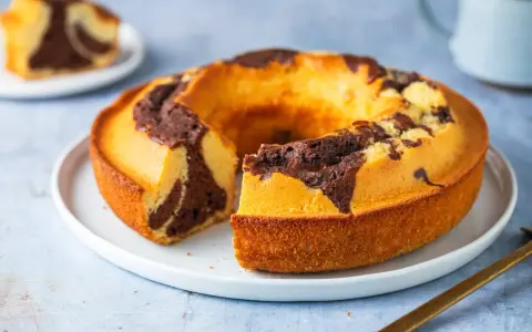Un ciambellone soffice bicolore, con un invitante contrasto tra pasta chiara e cacao, pronto per essere gustato.