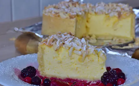 Una fetta di torta di riso cremosa, guarnita con mandorle a lamelle e frutti di bosco, su un piatto bianco.