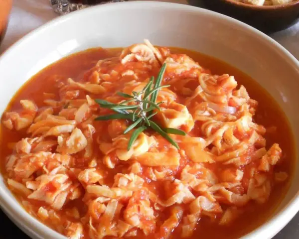 Trippa ricetta della nonna in un piatto bianco, guarnita con rosmarino. Un classico sapore di casa.