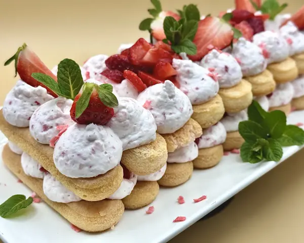 Delizioso tiramisù alle fragole, un dolce a strati con savoiardi, crema rosa e fragole fresche, guarnito con menta.