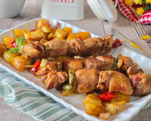 Spiedini di carne succulenti con patate arrosto e peperoni colorati, un piatto invitante e saporito.