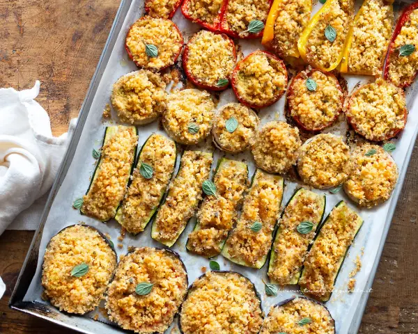 Verdure gratinate al forno: zucchine, melanzane, pomodori e peperoni ripieni di pangrattato e erbe aromatiche, cotti su una teglia.