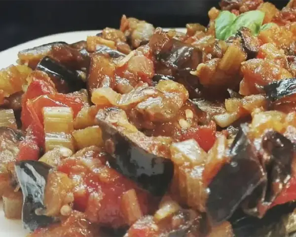 Un piatto invitante di caponata di verdure, con melanzane, pomodori e sedano cotti a puntino.
