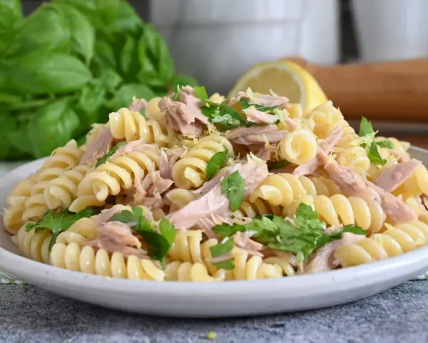 Un piatto di pasta fredda tonno, con fusilli, tonno sfilacciato, prezzemolo fresco e scorza di limone. Perfetta per un pranzo estivo.
