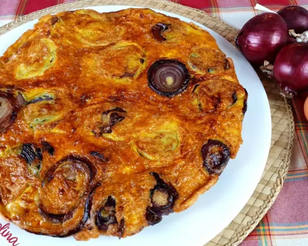 Frittata di pane dorata con cipolle rosse, uova e ingredienti freschi.