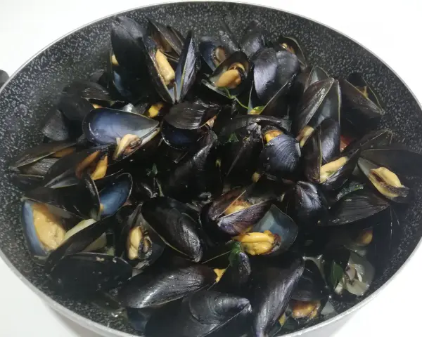Un saporito sautè di cozze appena cucinato, con gusci aperti che rivelano la polpa succulenta.