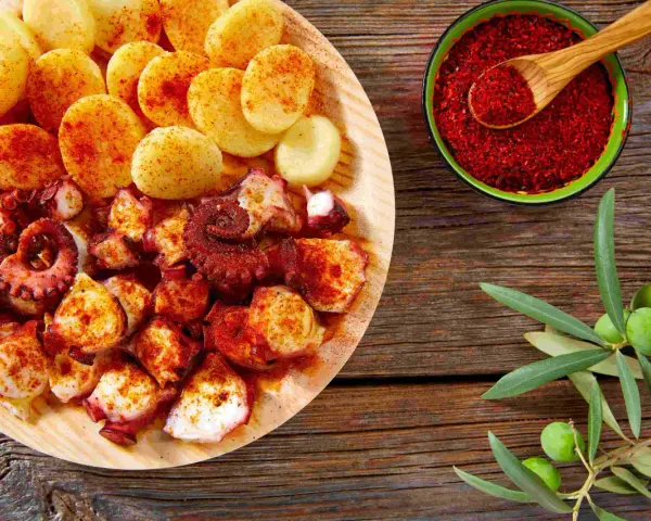 Piatto di polpo alla gallega con patate, paprika e rametto di ulivo.