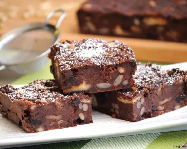 Fette di torta di pane al cioccolato, ricche di frutta secca e noci, spolverate di zucchero a velo.