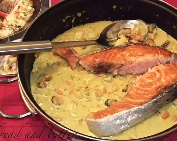 Delizioso trancio di salmone in padella con una cremosa salsa gialla e cozze.