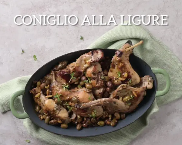 Un saporito coniglio alla ligure, cotto con olive e pinoli, servito in una casseruola verde.
