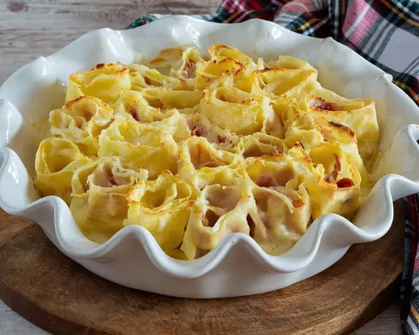 Deliziosi nidi di rondine ripieni di prosciutto e formaggio, cotti al forno in una teglia bianca.