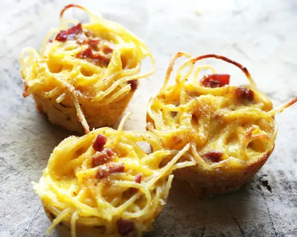 Tre deliziose frittate di pasta, dorate e con pezzetti di pancetta, pronte per essere gustate.