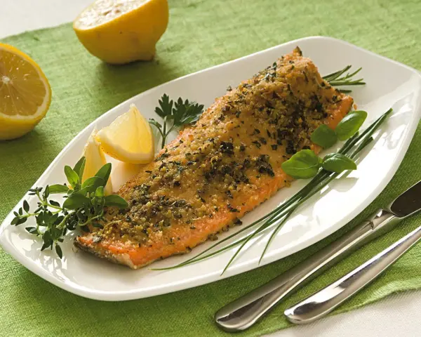 Deliziosa trota salmonata al forno, croccante e profumata, servita con limone fresco e erbe aromatiche.