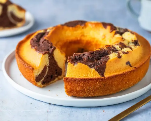 Un ciambellone soffice bicolore, con un invitante contrasto tra pasta chiara e cacao, pronto per essere gustato.
