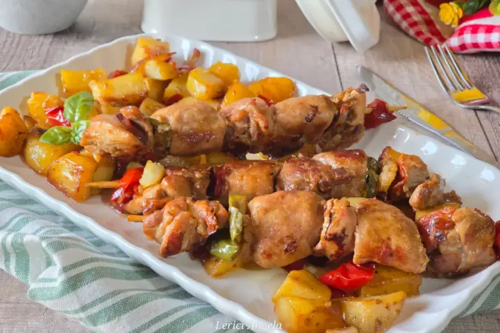 Spiedini di carne succulenti con patate arrosto e peperoni colorati, un piatto invitante e saporito.