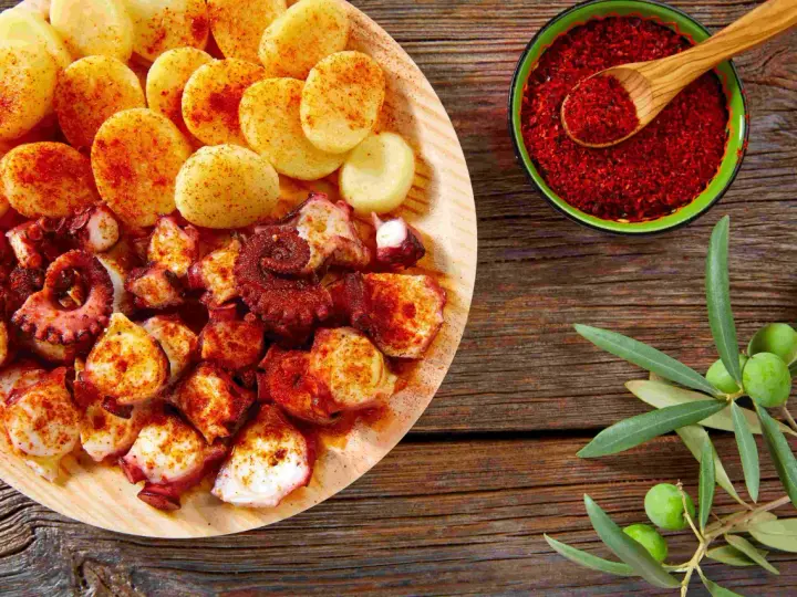 Piatto di polpo alla gallega con patate, paprika e rametto di ulivo.