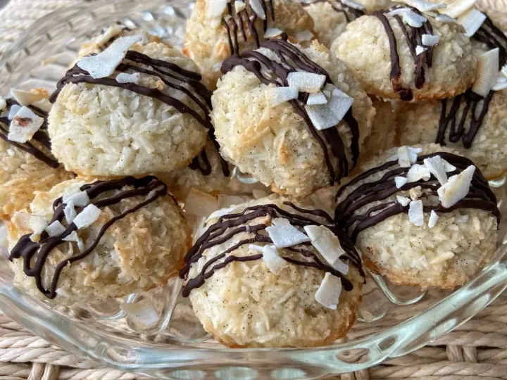 Deliziosi dolcetti al cocco, ricoperti da cioccolato fondente e scaglie di cocco croccante, su un piatto di vetro.