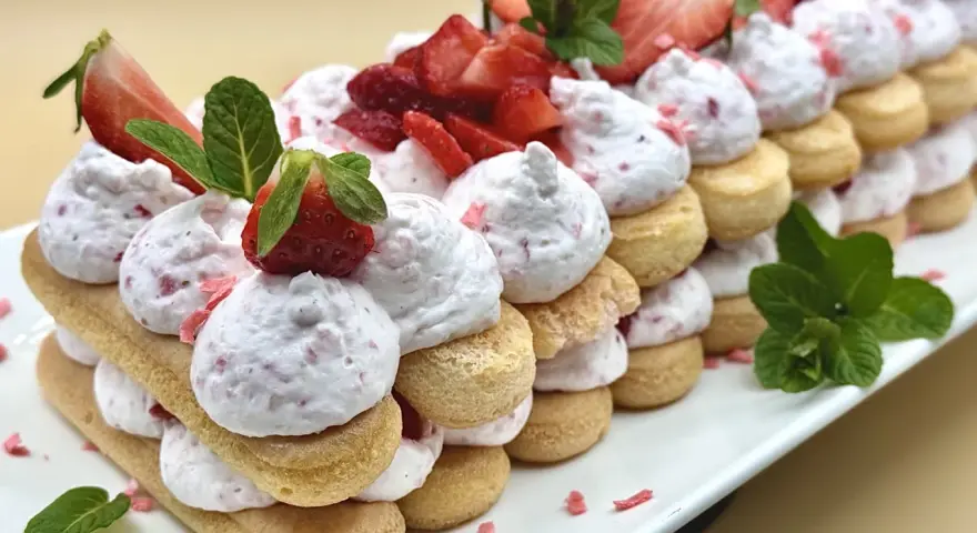 Delizioso tiramisù alle fragole, un dolce a strati con savoiardi, crema rosa e fragole fresche, guarnito con menta.