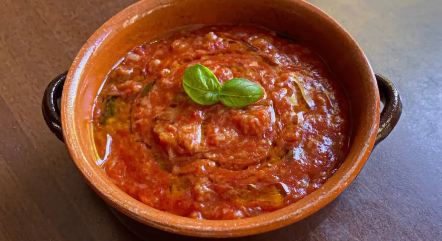 Piatto di pappa al pomodoro in terracotta, guarnito con basilico fresco. Un classico della cucina toscana.