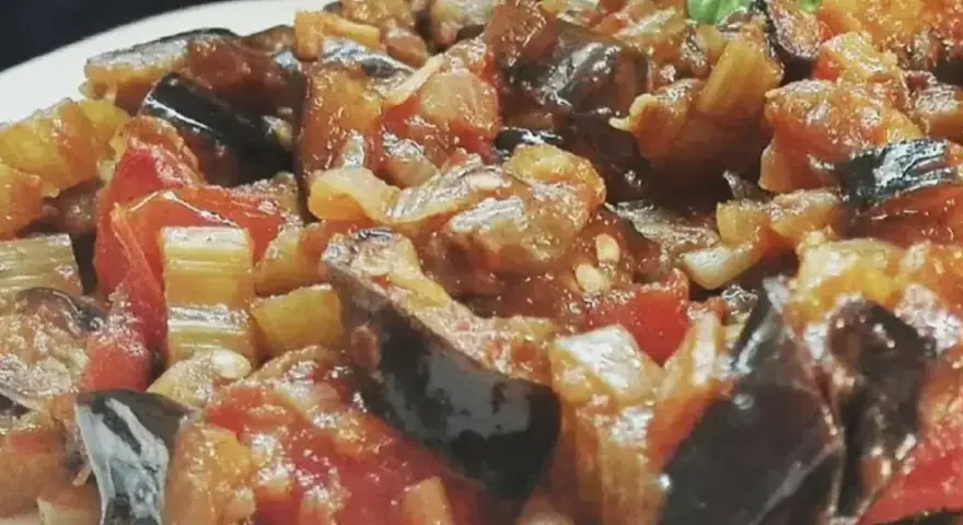 Un piatto invitante di caponata di verdure, con melanzane, pomodori e sedano cotti a puntino.