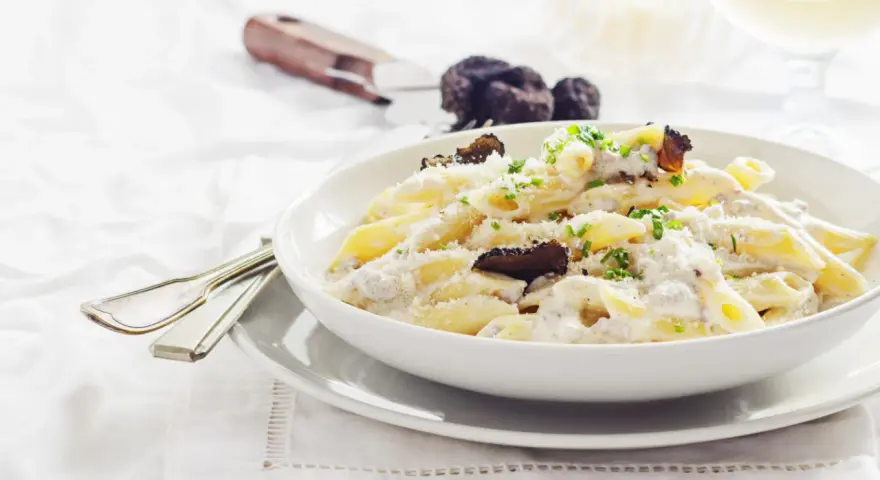 Penne cremose con funghi e tartufo nero, un piatto di pasta alla norcina che invita alla degustazione.