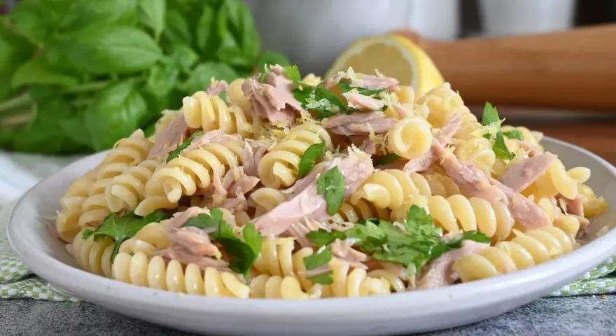 Un piatto di pasta fredda tonno, con fusilli, tonno sfilacciato, prezzemolo fresco e scorza di limone. Perfetta per un pranzo estivo.