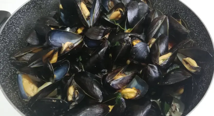 Un saporito sautè di cozze appena cucinato, con gusci aperti che rivelano la polpa succulenta.
