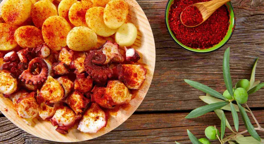 Piatto di polpo alla gallega con patate, paprika e rametto di ulivo.
